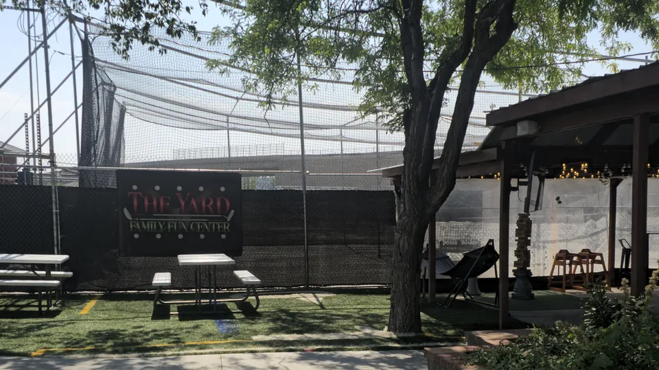Batting cage nets and the picnic area beneath The Yard Family Fun Center sign